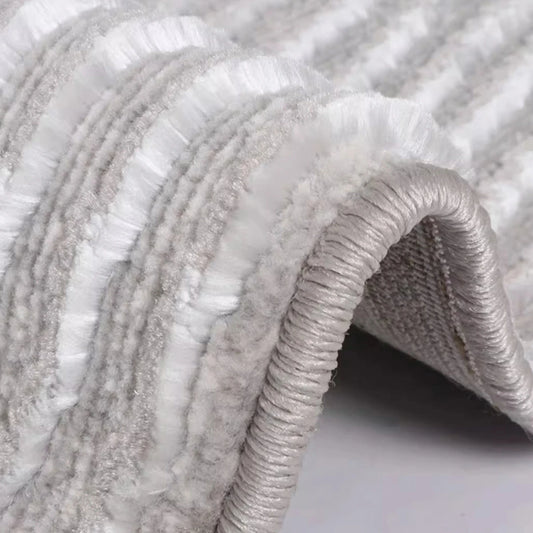 Ivory gray abstract area rug close-up showing the bound edge, soft textured pile, and flexible woven construction.