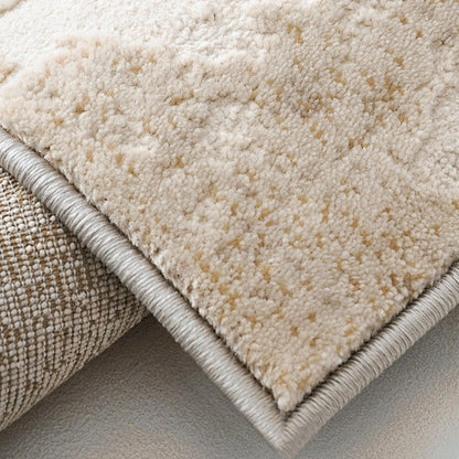 Folded corner detail of an ivory and gray abstract distressed area rug showing the woven backing and bound edge.