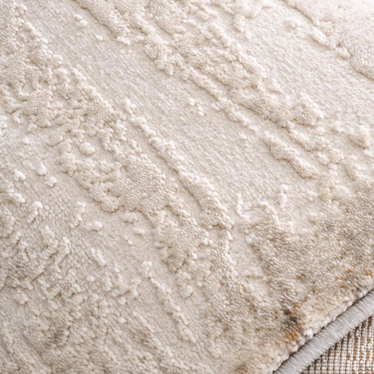 Close-up of an ivory and gray abstract distressed rug showing the soft textured pile and finished bound edge.