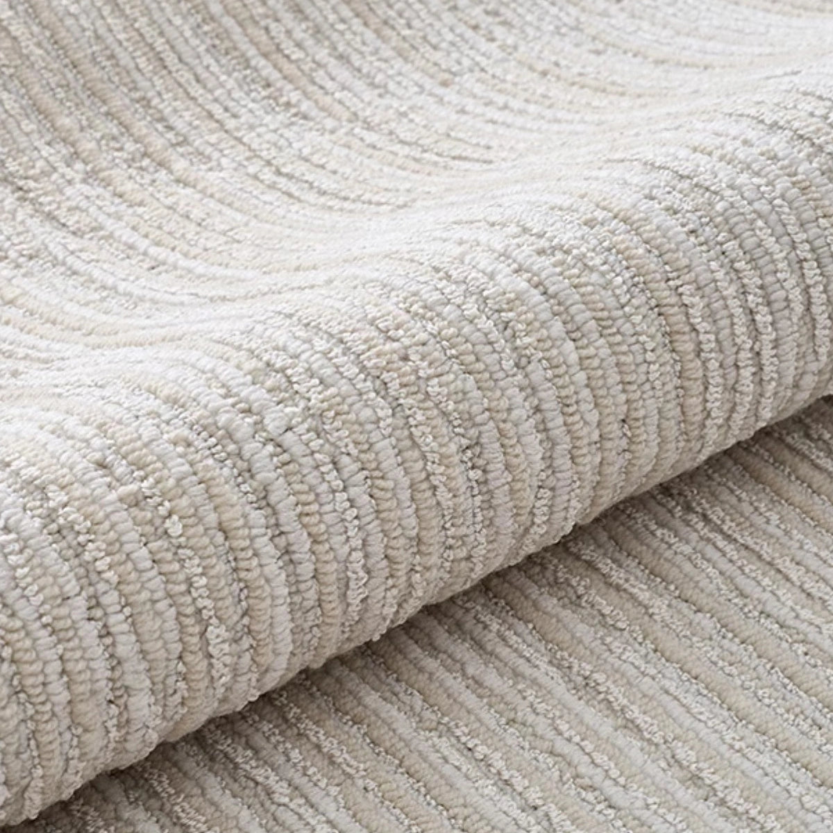 Ivory gray linear textured area rug rolled to show thick woven texture and soft neutral surface