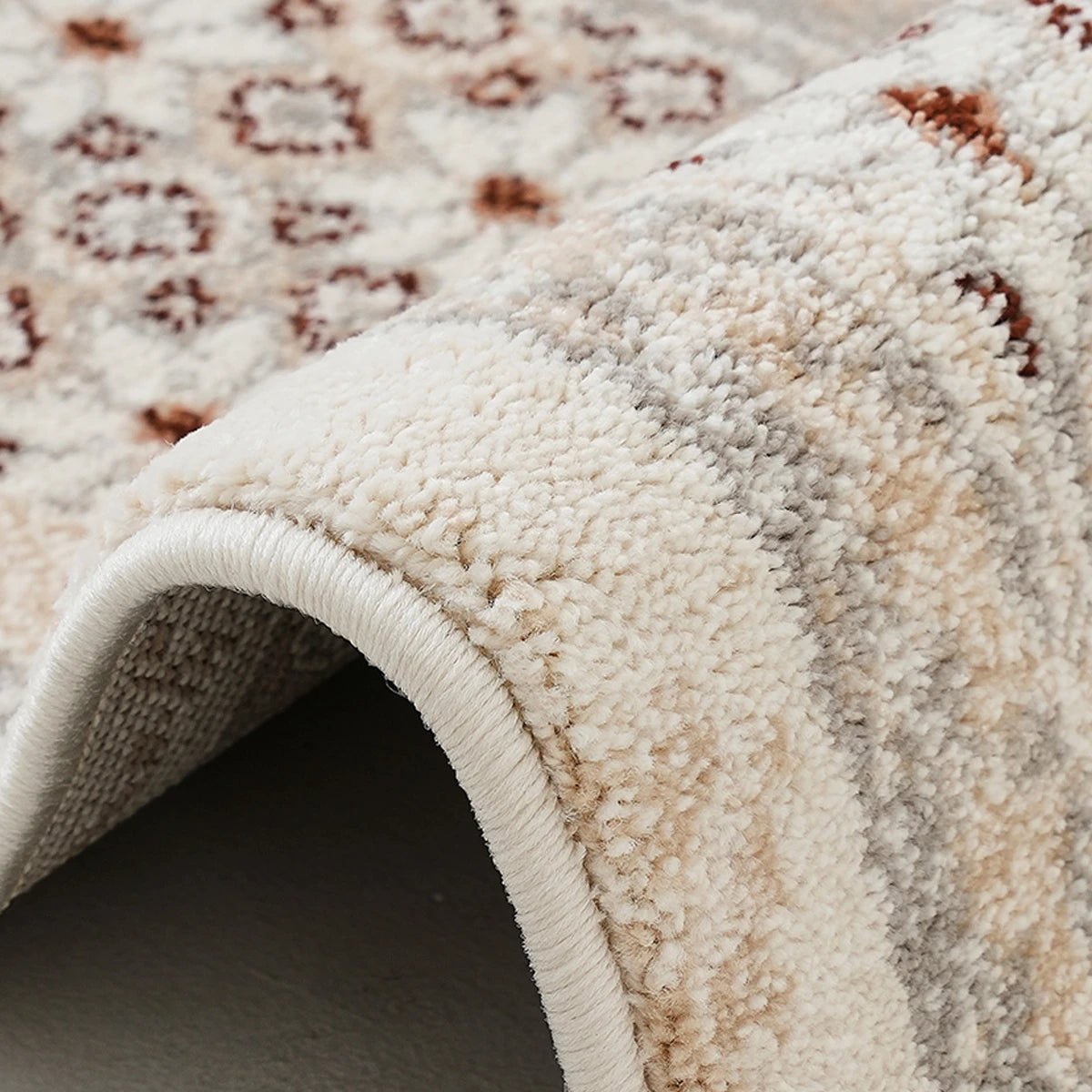 Ivory gray rust vintage area rug edge detail showing soft pile texture and finished binding