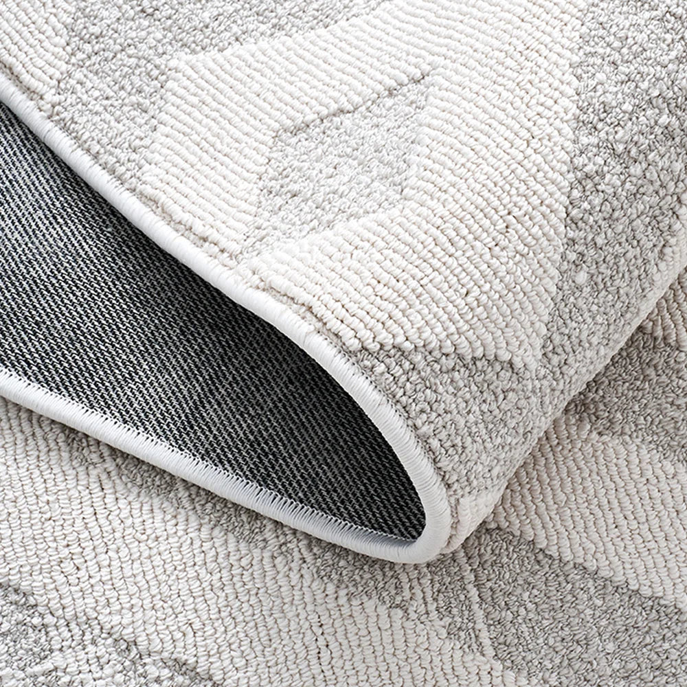 Back view of an ivory grey textured area rug showing durable woven backing and reinforced edge binding