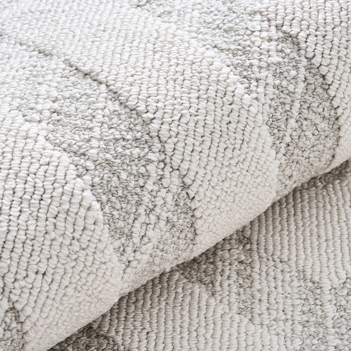 Detailed view of an ivory grey textured area rug featuring dense woven texture and dimensional pattern