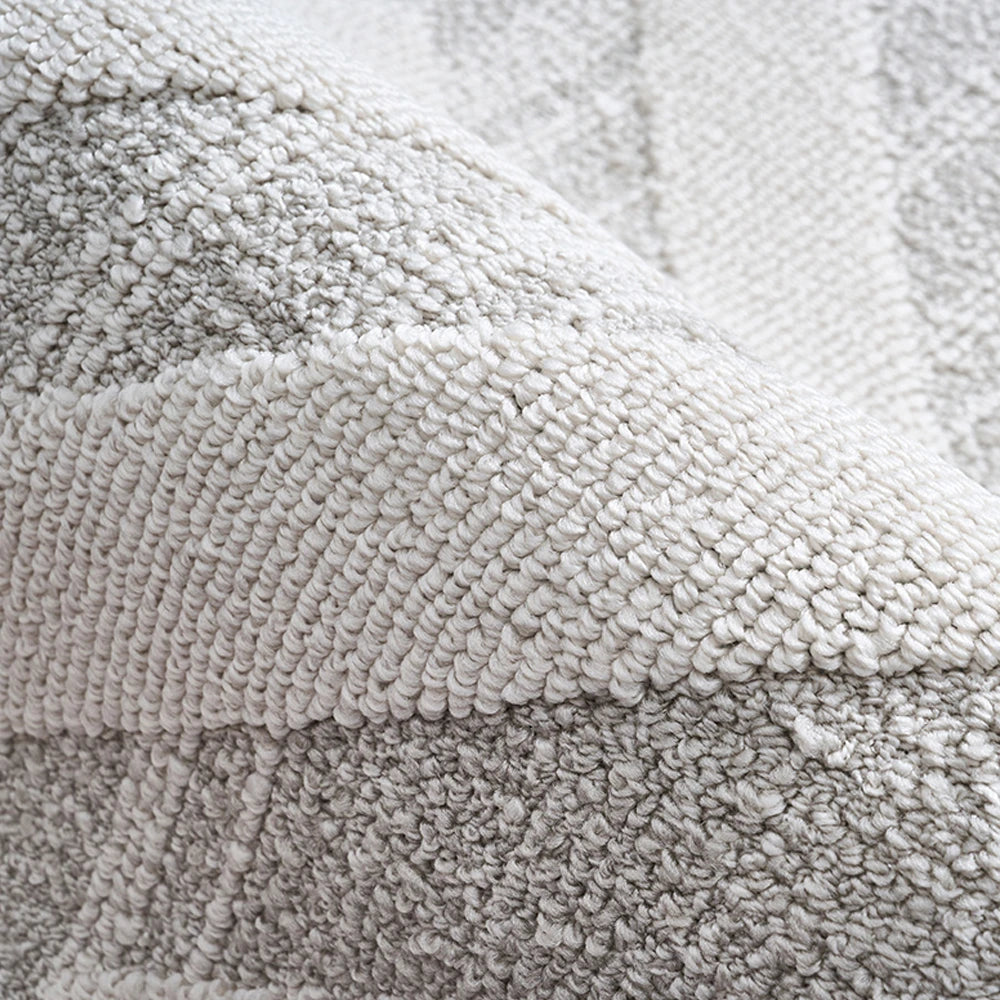 Close-up of an ivory grey textured area rug showing dense woven surface and raised texture pattern