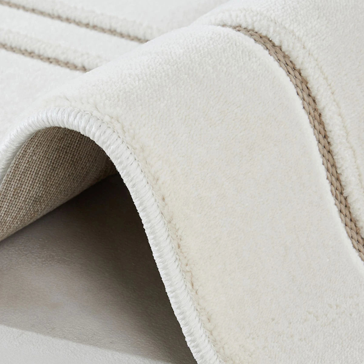 Ivory taupe geometric line area rug showing woven backing and finished edge detail