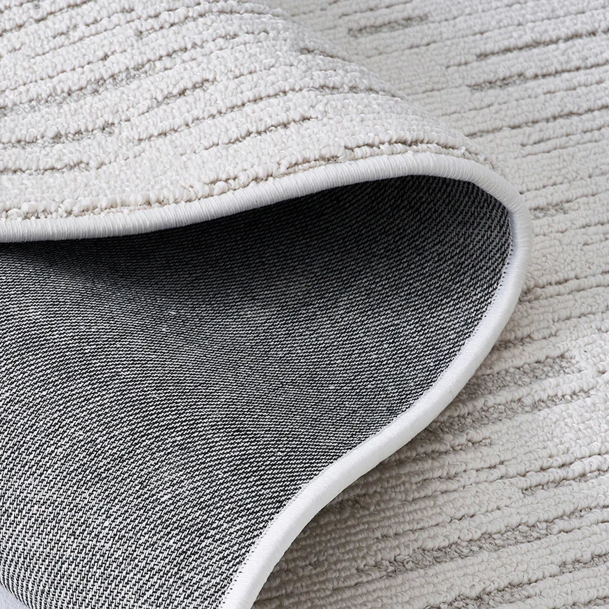 Back view of an ivory textured area rug showing durable woven backing and reinforced edge construction