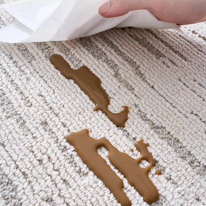 Ivory textured area rug demonstrating spill-resistant surface with liquid remaining on top of the fibers