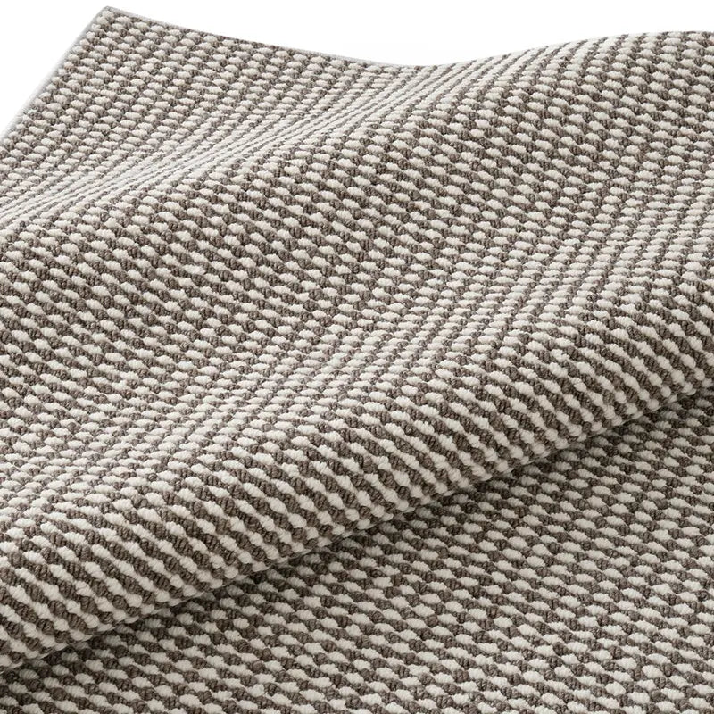 Close-up of folded wool blend rug showing looped texture and dense weaving in taupe and ivory
