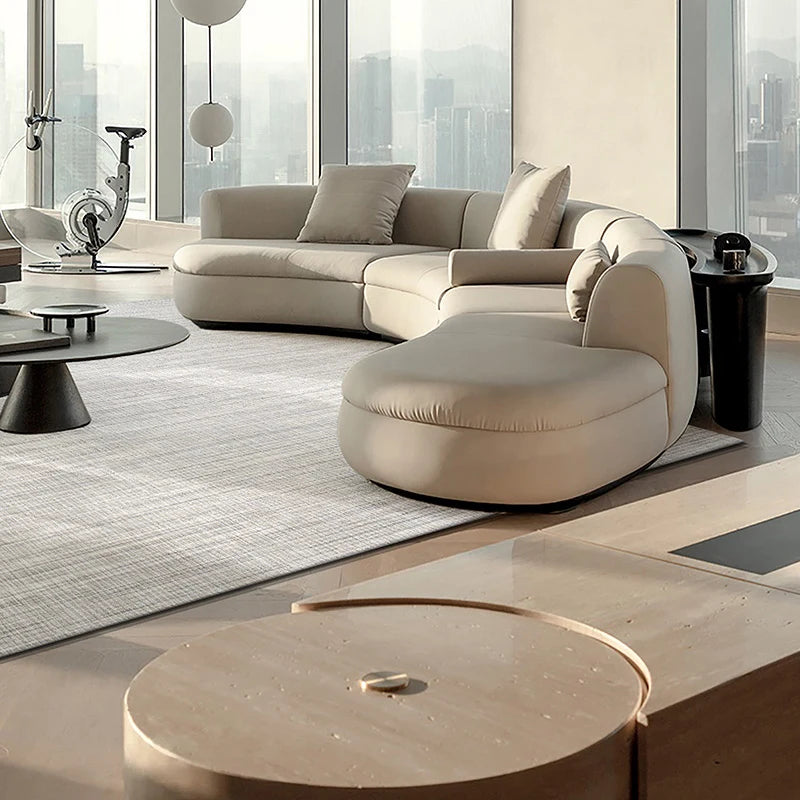 Luxurious modern living room with a soft beige woven rug that complements the curvy sectional sofa and skyline views
