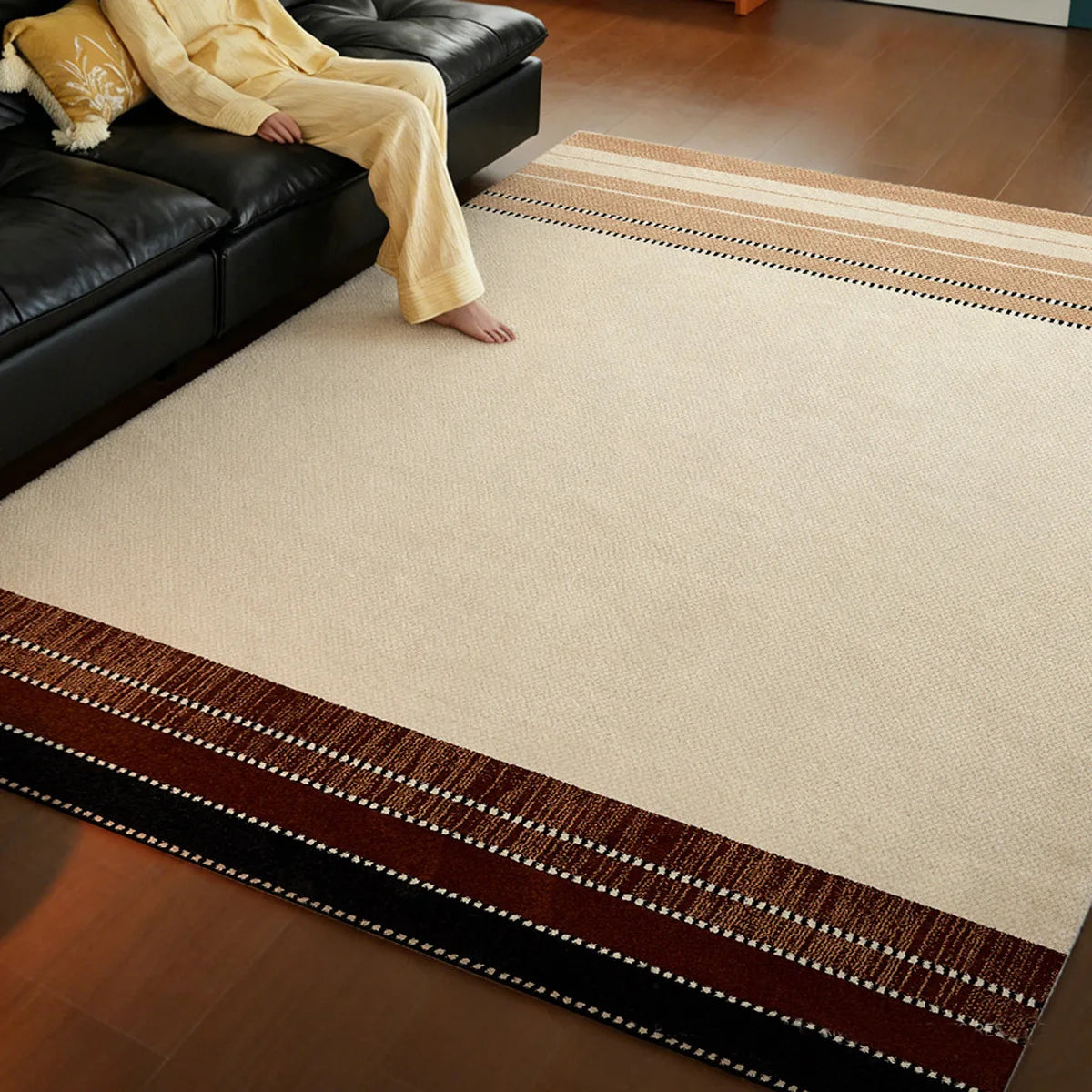 Cream beige border area rug styled with a black sofa and warm brown striped border
