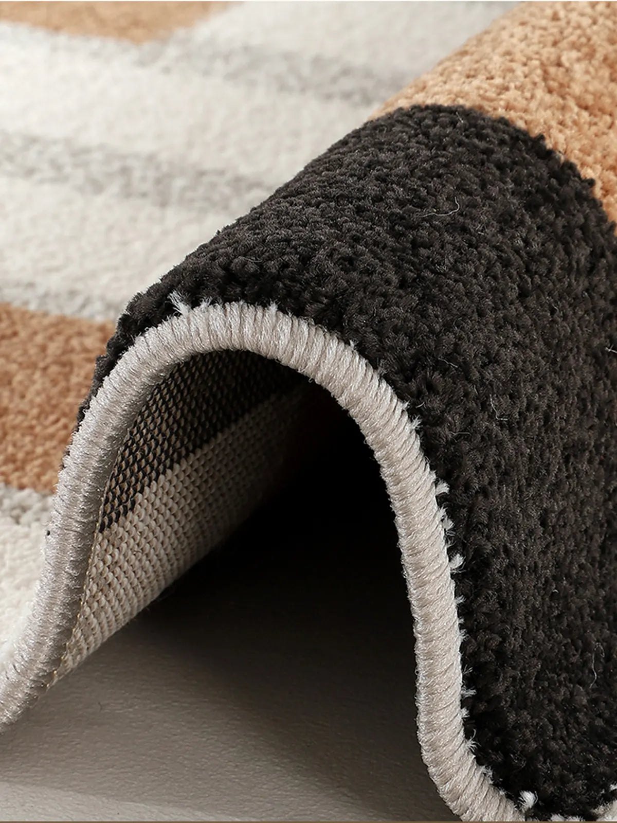 Close-up of a modern checkered rug showing thick pile, tight edge stitching, and black-brown color detail