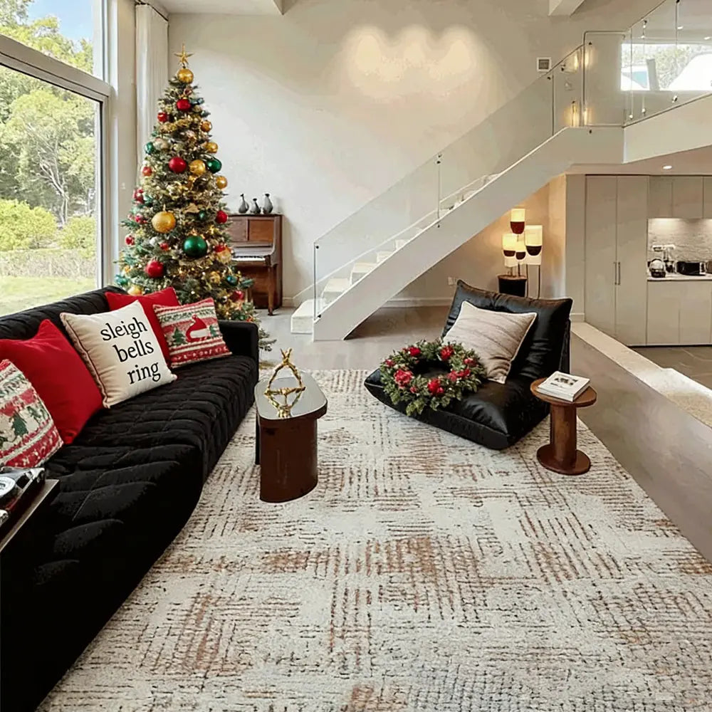 Modern geometric beige area rug in a bright living room with a Christmas tree, large window, and black sofa