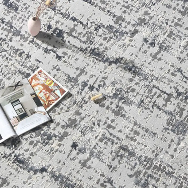Close-up of a modern gray textured area rug with a magazine and a decorative vase placed on it