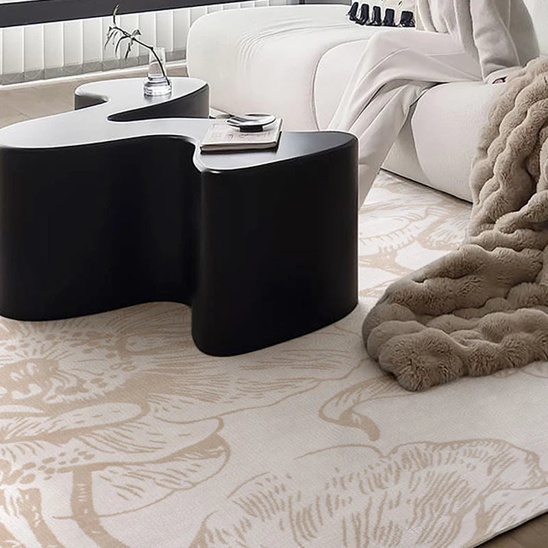 Modern living room with a beige floral rug under a black abstract coffee table and cozy blanket