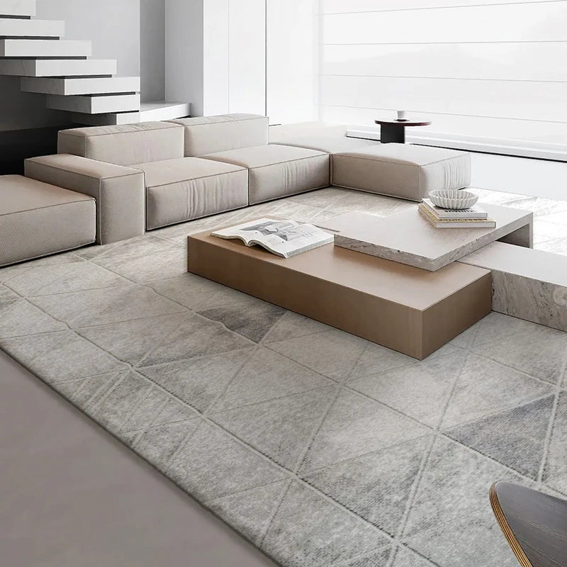 Modern minimalist living room featuring a grey geometric-patterned rug, neutral-toned sectional sofa, and contemporary decor with marble and wood elements