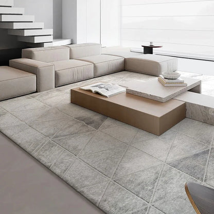 Modern minimalist living room featuring a grey geometric-patterned rug, neutral-toned sectional sofa, and contemporary decor with marble and wood elements