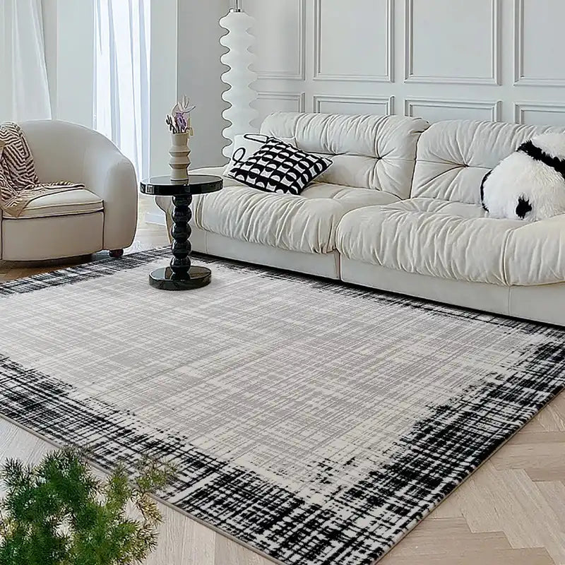 Bright living room with a modern neutral-toned rug and white sofa, complemented by black and white decorative pillows and sleek furnishings #color_Ivory