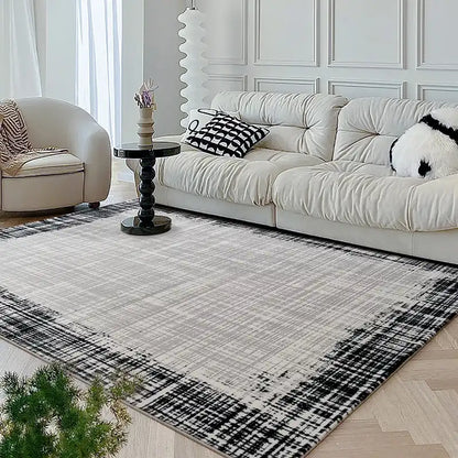Bright living room with a modern neutral-toned rug and white sofa, complemented by black and white decorative pillows and sleek furnishings 