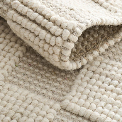 Natural ivory handwoven wool area rug folded detail showing thick chunky wool texture and raised woven pile.