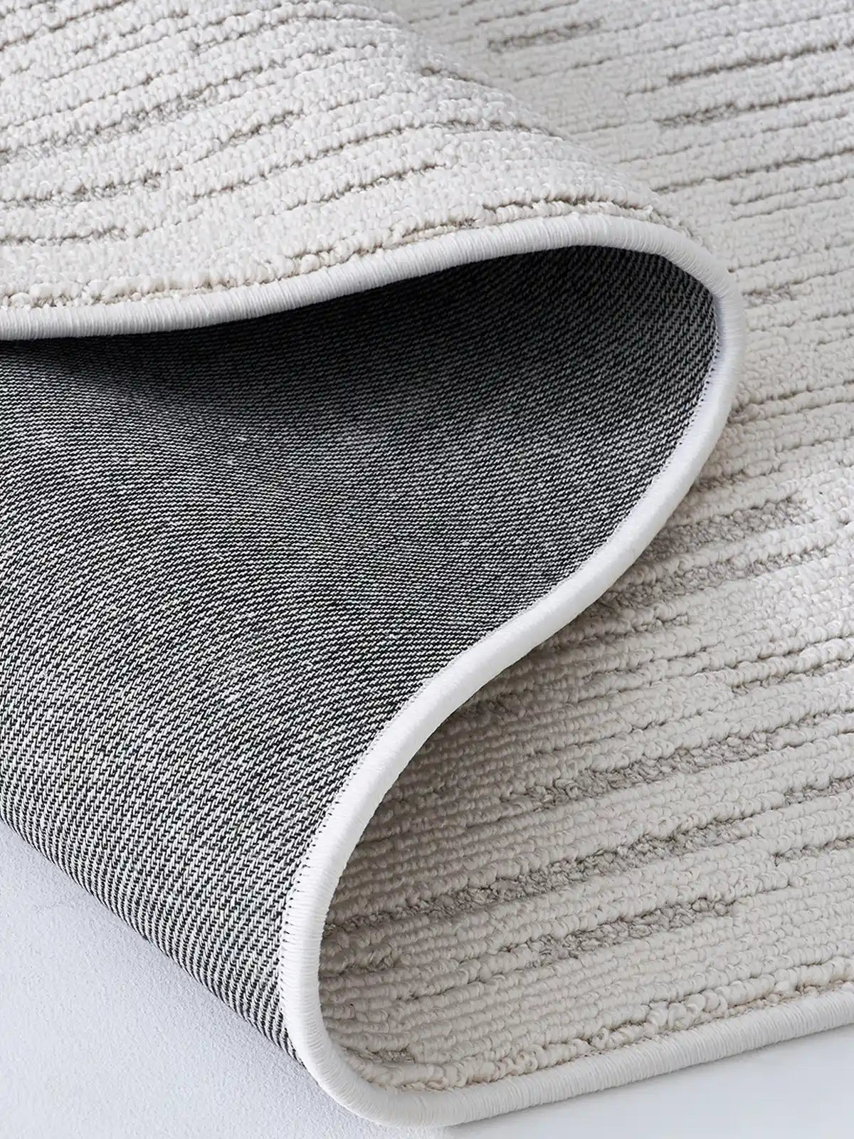 Close-up of a neutral striped rug showing detailed texture and durable backing
