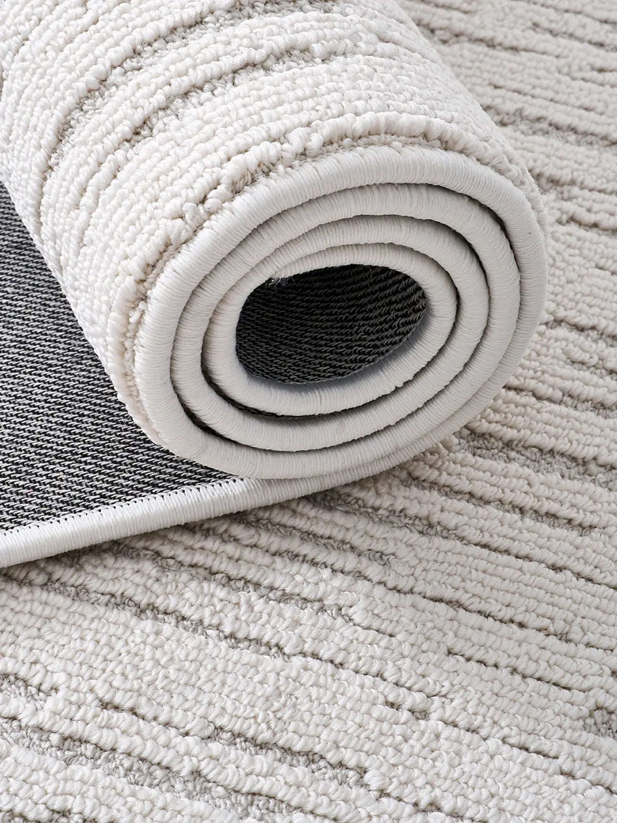 Close-up of a rolled neutral striped rug highlighting texture and durable backing