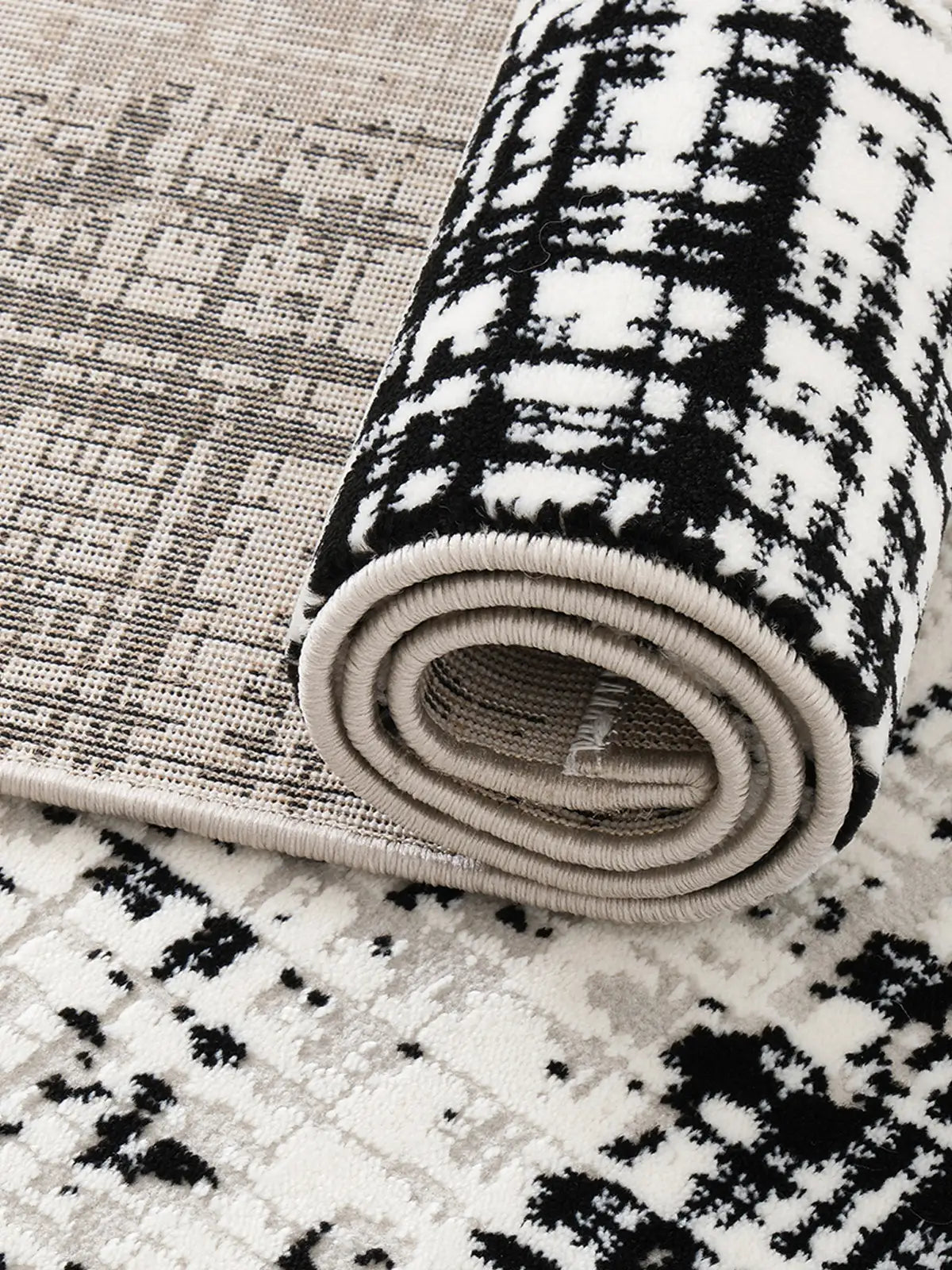 Close-up of a rolled rug showcasing its black and white pattern, soft texture, and durable backing design