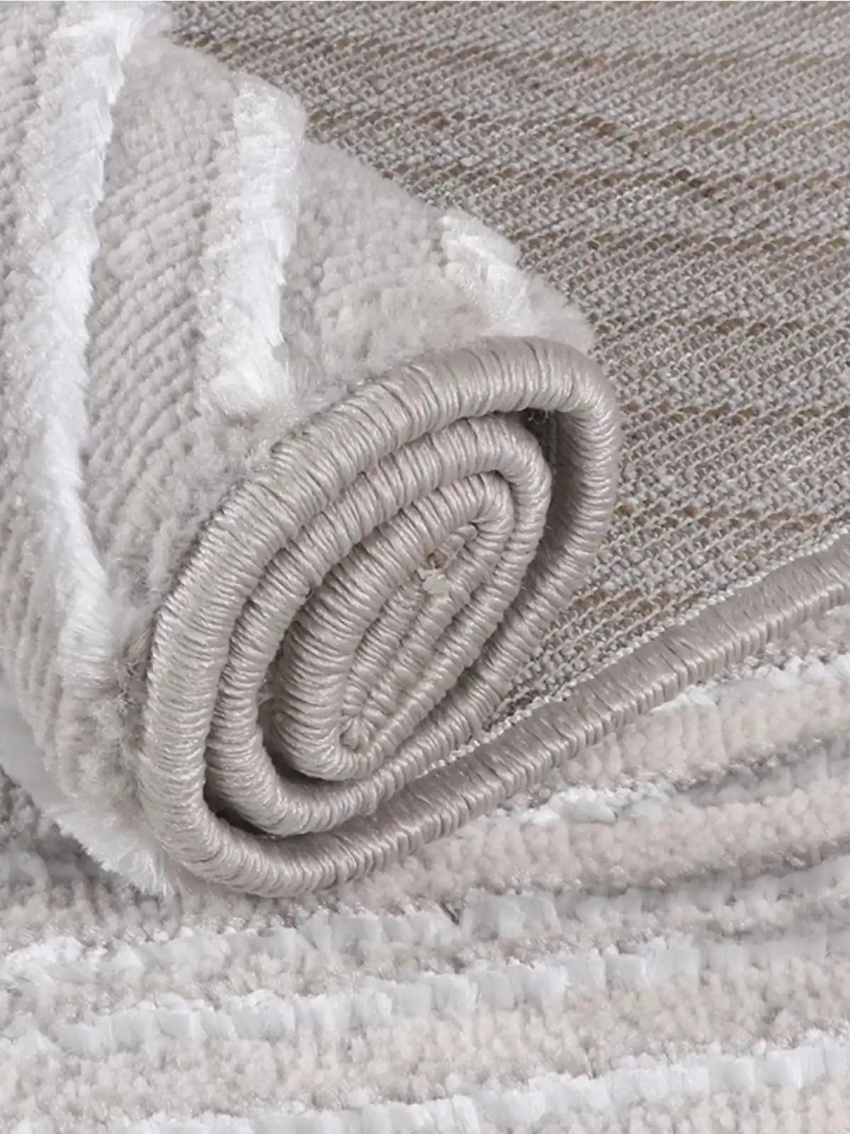 Close-up of a rolled gray rug with soft textures and reinforced edges, showcasing durability and elegant craftsmanship