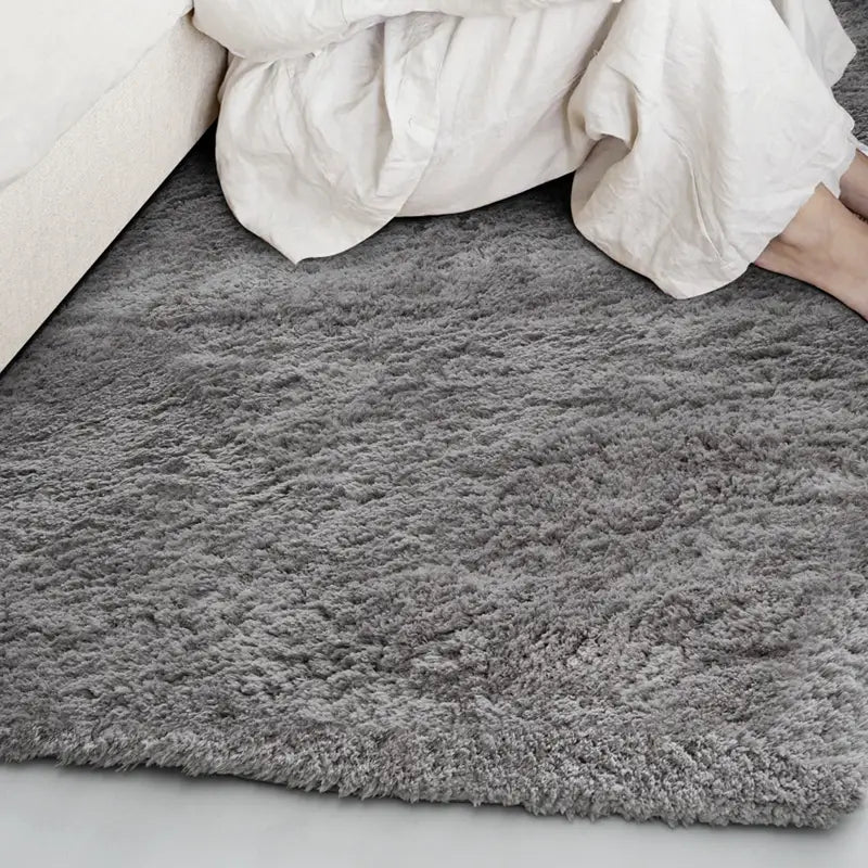 Soft gray shaggy rug placed next to a bed in a cozy bedroom #color_Charcoal Gray