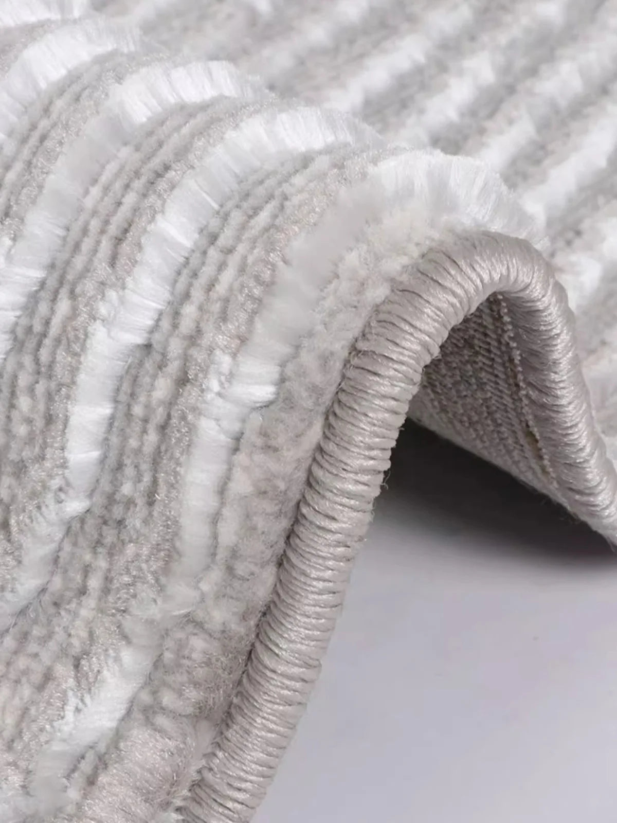 Close-up of a soft gray rug showcasing dense textures and reinforced edges, emphasizing durability and luxurious comfort