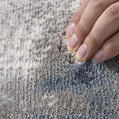 Hand pressing into soft pile of an area rug, demonstrating plush texture and comfortable feel for cozy living spaces #color_gray