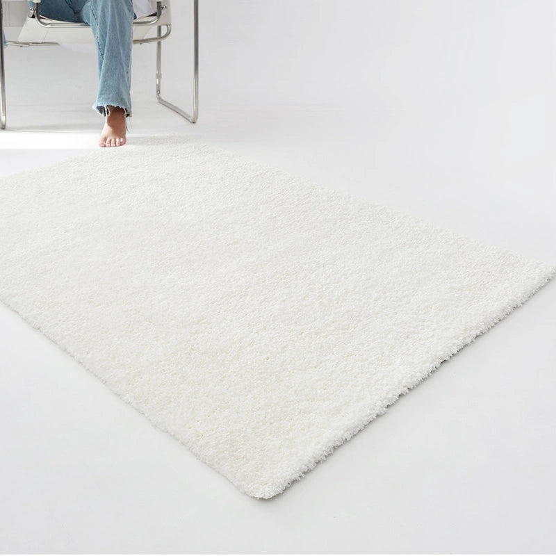 Minimalist white shaggy rug on a bright and modern floor setting, paired with a stylish chair #color_Ivory White