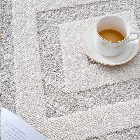 Close-up of a white area rug with a soft textured surface and subtle geometric patterns, styled with a teacup for an inviting look